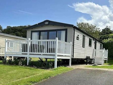 a holiday home with a deck and large windows at Doniford Bay - Holiday Accommodation 18610 Watchet