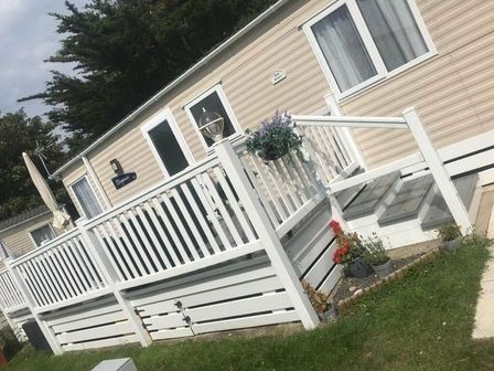 a exterior view of a mobile home with a deck and railing at Shorefield Country Park - Holiday Accommodation 18625 in Lymington