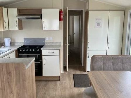 a kitchen area with cabinets, a stove, and a dining table at Butlins Minehead - Holiday Accommodation 18701, Minehead