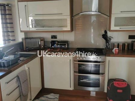 a kitchen with a stove, microwave, and utensils at Palins Holiday Park - Holiday Accommodation 19189 Towyn