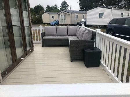 a patio with a grey sectional sofa and a small table at Seashore Holiday Park - Holiday Accommodation 19204 in Great Yarmouth