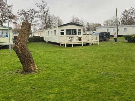 a cabin with a deck in a grassy area at Butlins Skegness - Holiday Accommodation 19332 Skegness