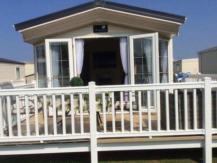 a holiday home with a deck and glass doors at Lido Beach Holiday Park - Holiday Accommodation 19352 in Prestatyn