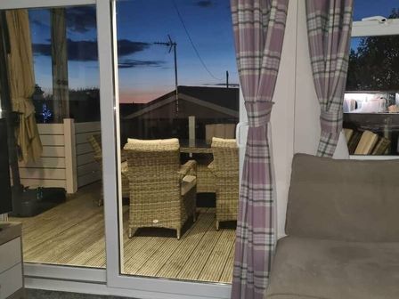 a seating area with a view of wicker chairs on a deck at Barmouth Bay Holiday Village - Holiday Accommodation 19354 Talybont