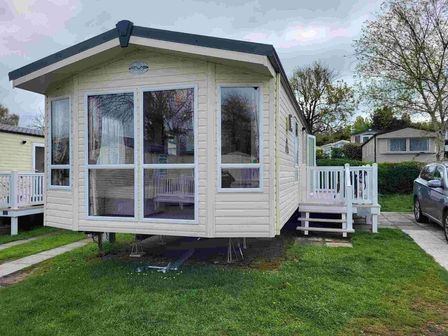 a static caravan with large windows and a wooden deck at Rockley Park - Holiday Accommodation 19381 in Poole
