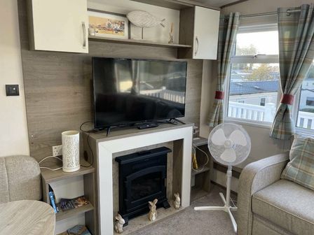 a living room with a television, a fireplace, and chairs at Rockley Park - Holiday Accommodation 19386, Poole