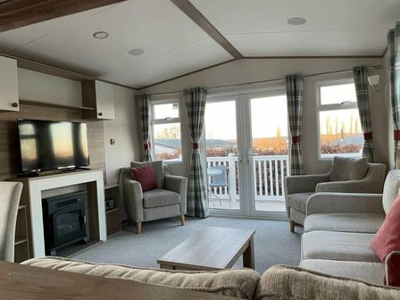 a living room with a television, fireplace, and seating area at Rockley Park - Holiday Accommodation 19406 in Poole
