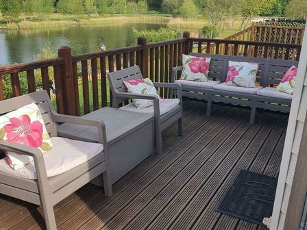 a porch with seating and cushions overlooking a pond at 7 Lakes Country Park - Holiday Accommodation 19456 Scunthorpe