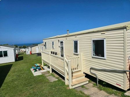 a mobile home with a deck in a grassy area at Reighton Sands Holiday Park - Holiday Accommodation 19531, Filey