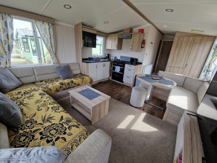a living room with a sofa, coffee table, kitchen area, and dining space at Clarach Bay Holiday Village - Holiday Accommodation 19626 in Aberystwyth