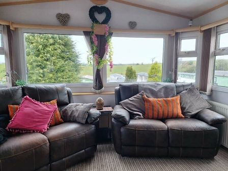 a seating area with two sofas and decorative pillows at Todber Valley Holiday Park - Holiday Accommodation 19664, Clitheroe