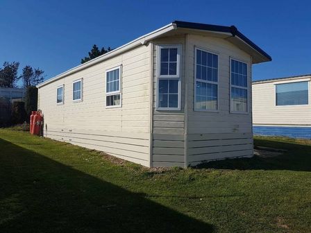 a caravan with multiple windows and gas canisters outside at Trimingham House Caravan Park - Holiday Accommodation 19782 Trimingham