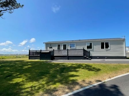 a holiday home with a deck and grassy area at Newquay Holiday Park - Holiday Accommodation 19866, Newquay