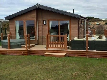 a wooden lodge with a deck and seating area at Hafan y Mor Haven - Holiday Accommodation 19898, Pwllheli
