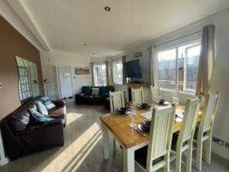 a dining area with a table and chairs next to a sofa and windows at St Minver Holiday Park - Holiday Accommodation 19947 in Wadebridge