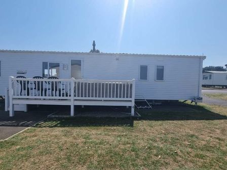 a white mobile home with a deck and seating area at Seashore Holiday Park - Holiday Accommodation 20075 in Great Yarmouth