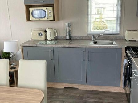 a kitchen with a sink, appliances, and cabinets at Lyons Moelfre View - Holiday Accommodation 20226 Talybont