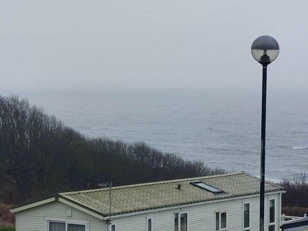 a coastal view with a mobile home and street lamp at Reighton Sands Holiday Park - Holiday Accommodation 2023 Filey