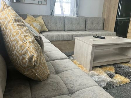 a living room with a gray sectional sofa and a wooden coffee table at Par Sands Holiday Park - Holiday Accommodation 20261, Par