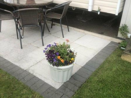 a flower pot with various colored flowers next to a patio table and chairs at Bryn Morfa - Holiday Accommodation 20316, Conwy