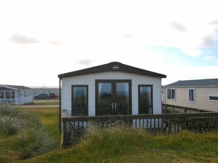 a holiday cabin with a deck and large windows at Perran Sands - Holiday Accommodation 20514 in Perranporth