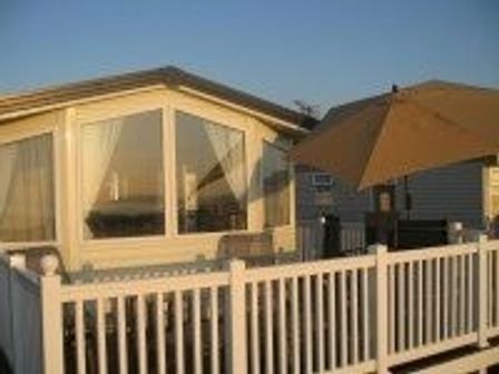 a holiday home with a deck and an umbrella on a terrace at Doniford Bay - Holiday Accommodation 207, Watchet