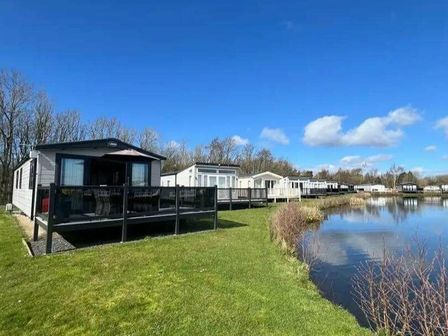 a row of holiday homes by a pond at Lakeland Leisure Park - Holiday Accommodation 20788 Flookburgh