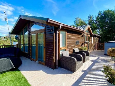 a wooden cabin with a deck and outdoor furniture at Hafan y Mor Haven - Holiday Accommodation 20860, Pwllheli