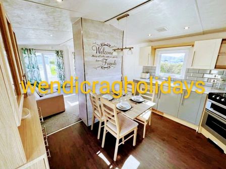 a dining area with a table set for meals and a kitchen at Ty Mawr Holiday Park - Holiday Accommodation 20936 in Towyn