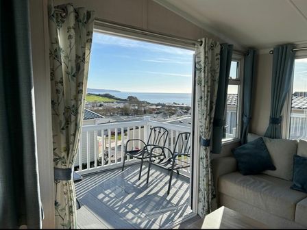 a seating area with a view of the sea and landscape at Ladram Bay Holiday Park - Holiday Accommodation 20944 Otterton