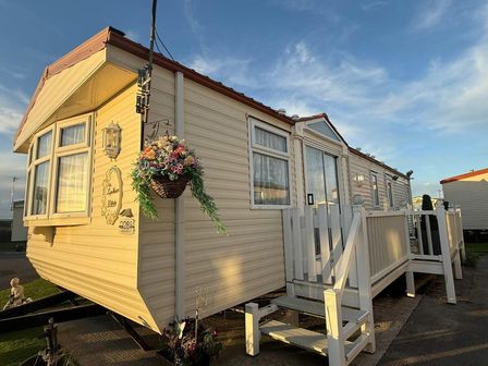 a caravan with a small porch and flowers hanging at Happy Days Caravan Park - Holiday Accommodation 20971 Towyn