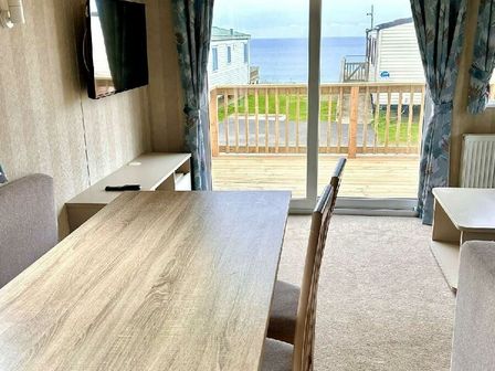a dining area with a table and chairs overlooking the sea at Perran Sands - Holiday Accommodation 21088, Perranporth