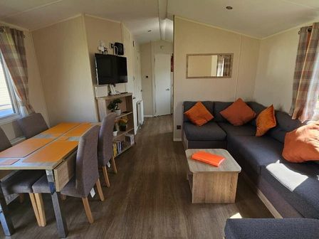a living room with a sofa, dining table, and television at Broadland Sands - Holiday Accommodation 21136 in Corton, Lowestoft