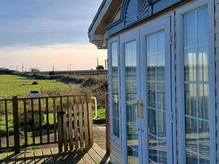 a view of a building with large windows overlooking a green field at Lowlands Farm (private land) - Holiday Accommodation 21161 Bacton