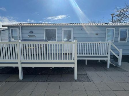 a holiday home with a white railing on a patio at Reighton Sands Holiday Park - Holiday Accommodation 21198 in Filey