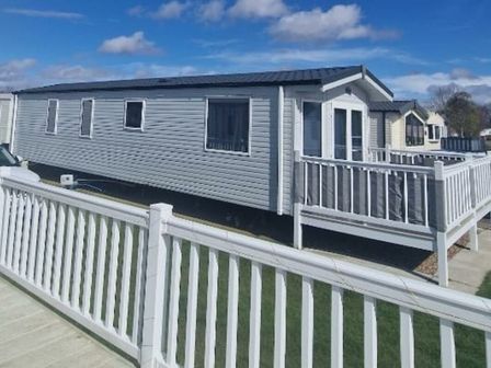 a mobile home with a deck and white fence at Cleethorpes Beach Holiday Park - Holiday Accommodation 21237, Cleethorpes