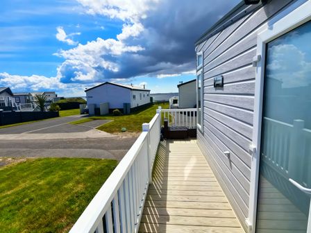 A deck with a pathway and houses in the background at Ocean Edge Leisure Park - Holiday Accommodation 21286 Morecambe