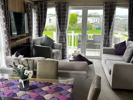 a living room with a sofa, armchair, and dining table at Marine Holiday Park - Holiday Accommodation 21289, Rhyl
