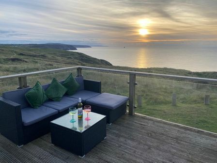 a seating area with drinks on a table overlooking a sunset at Perran Sands - Holiday Accommodation 21444 in Perranporth