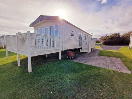a holiday home with a deck on a grassy area at Crimdon Dene Holiday Park - Holiday Accommodation 21463 Hartlepool