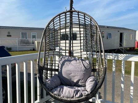 a hanging chair with cushions on a balcony at Greenacres Holiday Park - Holiday Accommodation 21467 in Morfa Bychan