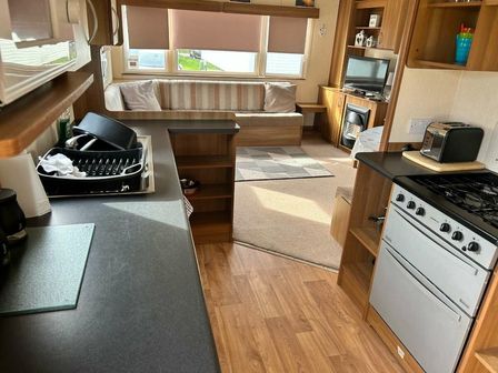 a kitchen area with a stove, microwave, and seating at Ty Mawr Holiday Park - Holiday Accommodation 21752 Towyn