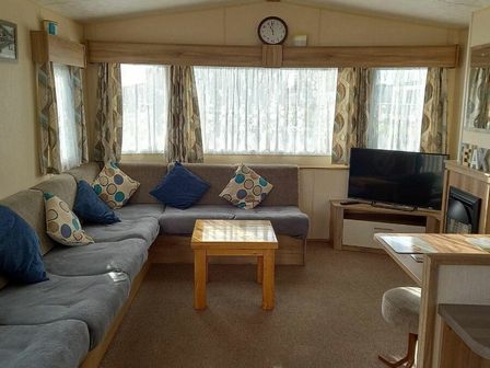 a living room with a sectional sofa and a television at North Shore Holiday Centre - Holiday Accommodation 21789, Skegness