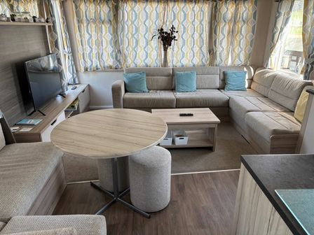 a living room with a sectional sofa and a round dining table at Clarach Bay Holiday Village - Holiday Accommodation 21919, Aberystwyth