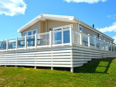 a holiday chalet with a deck and outdoor seating at Devon Cliffs Holiday Park - Holiday Accommodation 22011, Sandy Bay, Exmouth