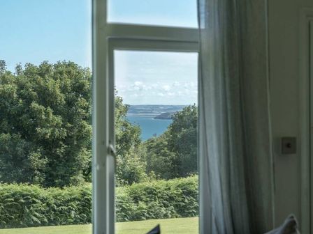 a view of the sea through a window with trees in the foreground at Bideford Bay Holiday Park - Holiday Accommodation 22089 Bucks Cross