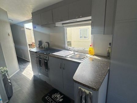 a kitchen with gray cabinets and a countertop at Golden Gate Holiday Centre - Holiday Accommodation 22148 in Towyn