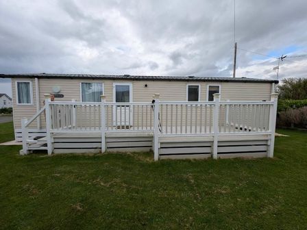 a caravan with a white deck on a grassy area at Ty Gwyn Caravan Park - Holiday Accommodation 22189 Abergele