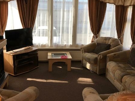 a living room with a TV and two armchairs at Lyons Robin Hood - Holiday Accommodation 22312 PRESTATYN