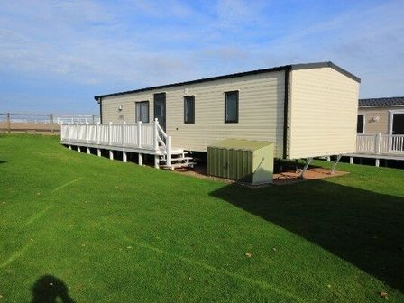 a mobile home with a deck and green grass at Hoburne Blue Anchor - Holiday Accommodation 2262, Minehead